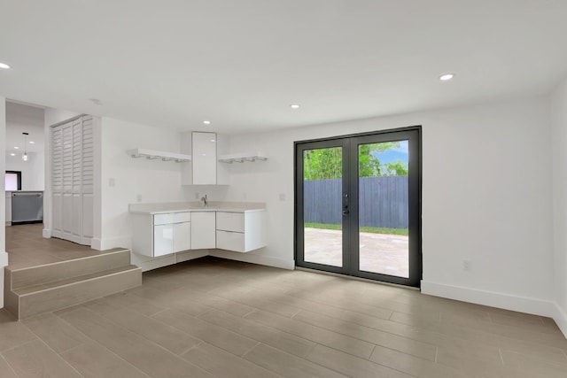 unfurnished living room with sink, light hardwood / wood-style flooring, and french doors