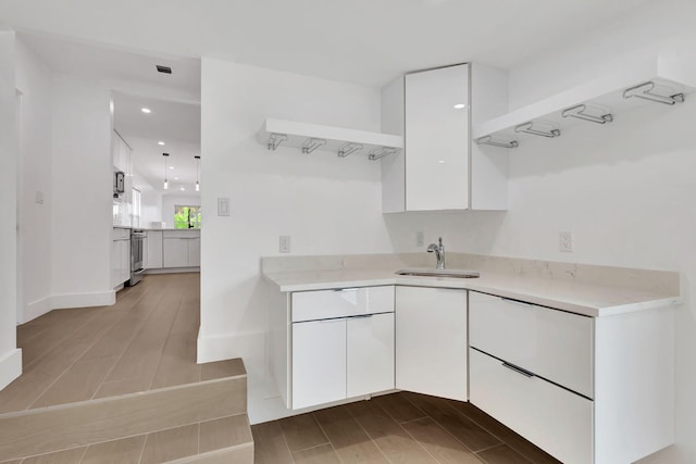 kitchen featuring white cabinetry, sink, stainless steel range oven, and light hardwood / wood-style flooring