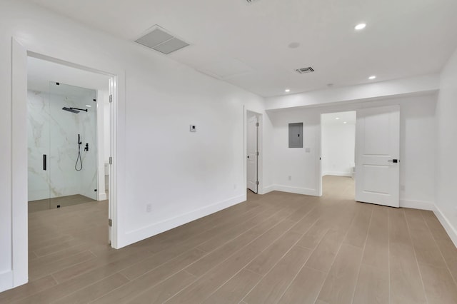 spare room featuring electric panel and light hardwood / wood-style floors