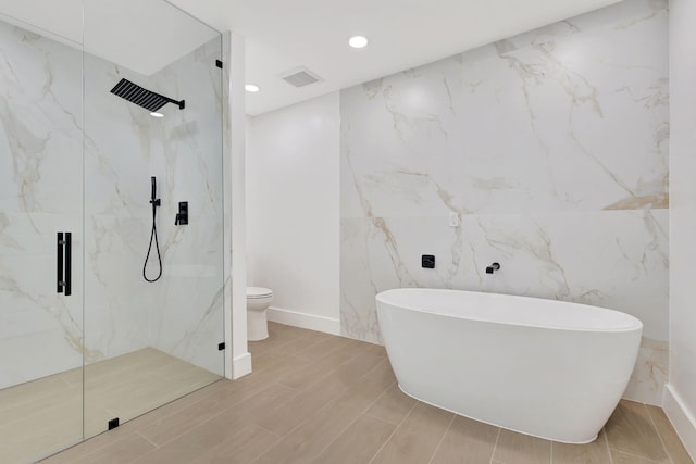 bathroom featuring independent shower and bath, toilet, and tile walls