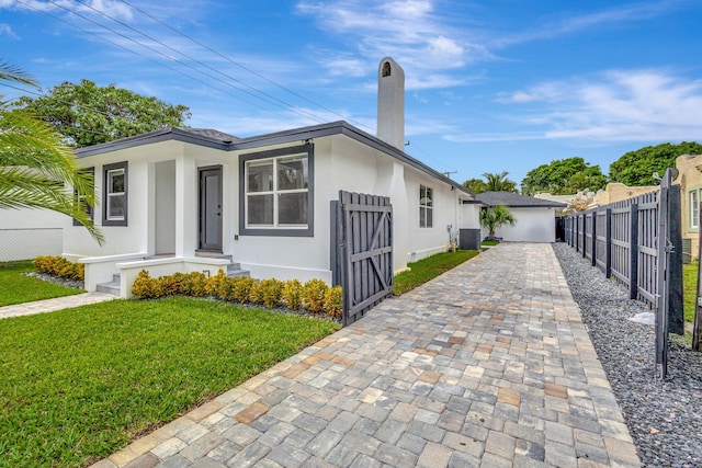 view of front of home with central AC unit and a front lawn