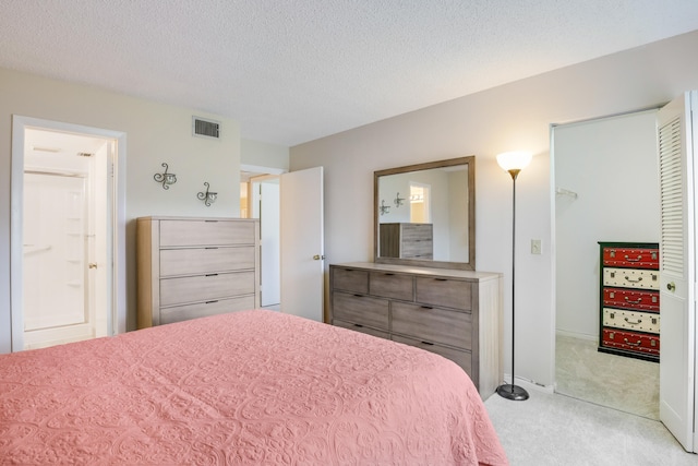 bedroom featuring a textured ceiling, light carpet, and ensuite bathroom