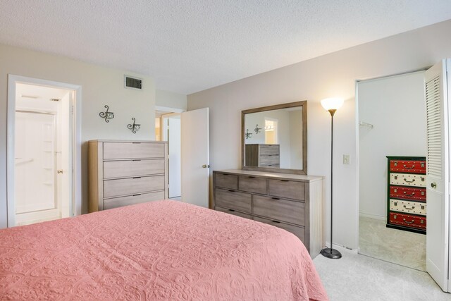 bedroom featuring a textured ceiling, light carpet, a closet, and a spacious closet