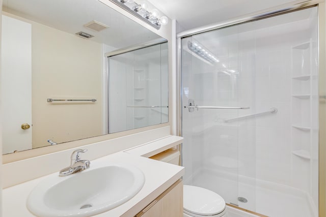 bathroom with walk in shower, vanity, and toilet