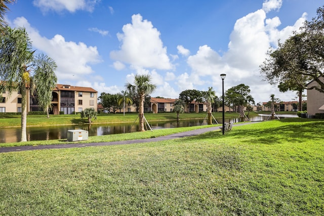 surrounding community with a water view and a lawn