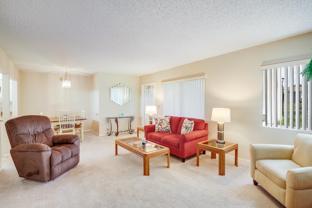 living room with a chandelier, a textured ceiling, and light colored carpet