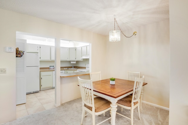 dining space featuring a notable chandelier, sink, light colored carpet, and a textured ceiling