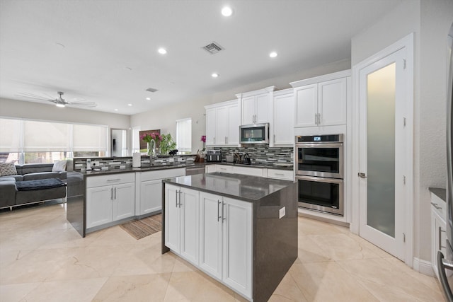 kitchen with stainless steel appliances, kitchen peninsula, tasteful backsplash, ceiling fan, and white cabinetry