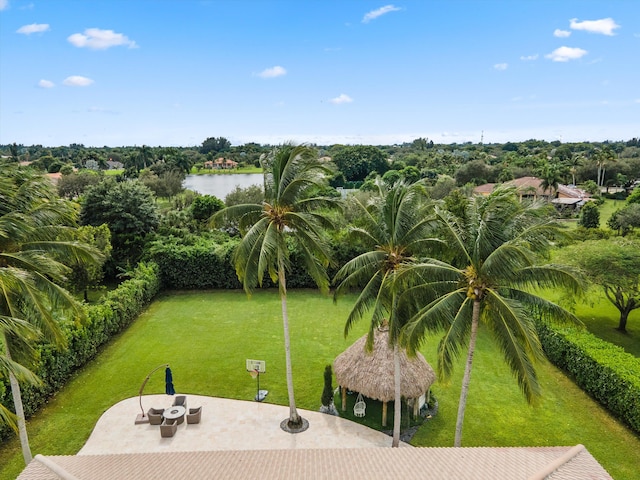 view of property's community with a water view, a lawn, and a patio area