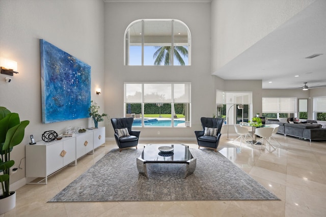 living room featuring ceiling fan and a high ceiling