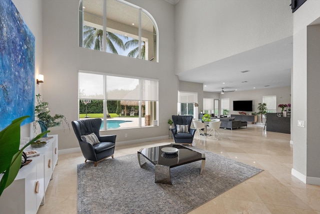 living room featuring ceiling fan and a high ceiling