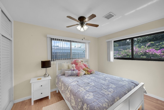 bedroom with a closet, light wood-type flooring, multiple windows, and ceiling fan