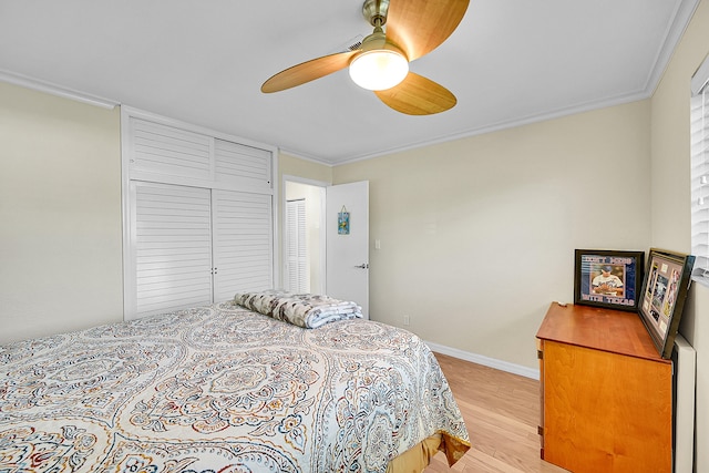 bedroom featuring ornamental molding, light hardwood / wood-style floors, ceiling fan, and a closet