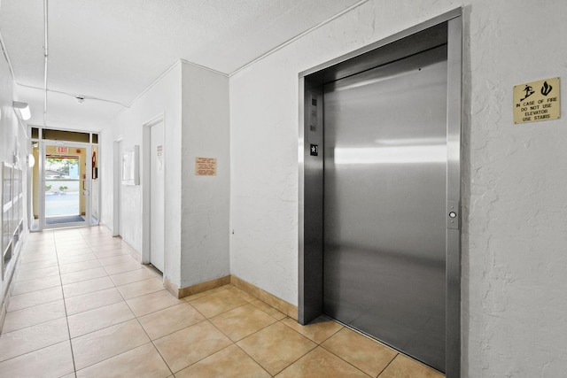 hallway with elevator and light tile patterned floors