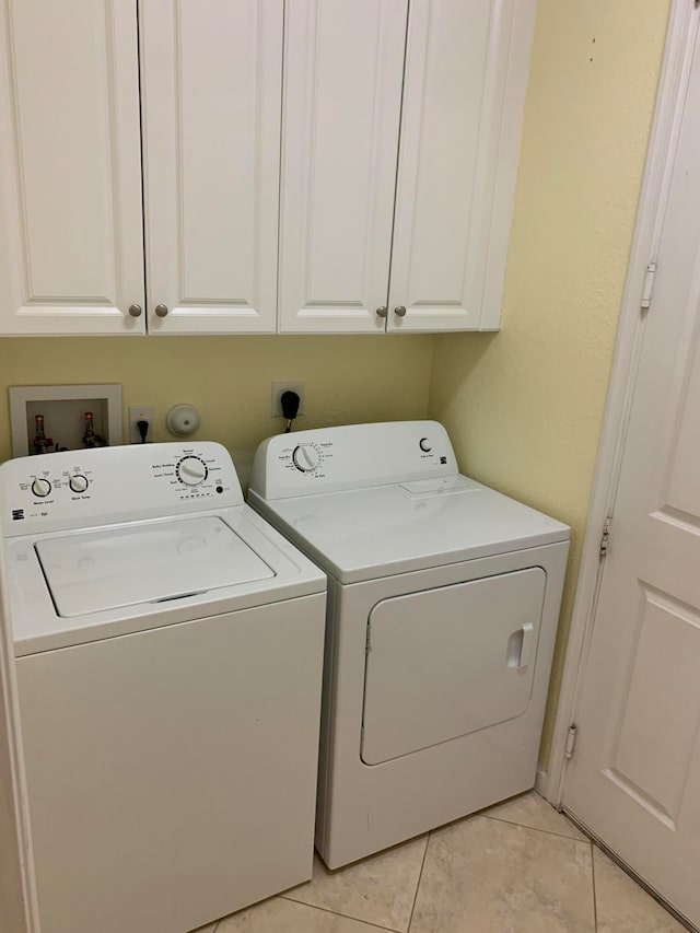 clothes washing area with cabinets, light tile patterned flooring, and independent washer and dryer