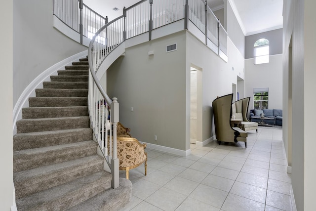 staircase featuring a high ceiling, tile patterned floors, and ornamental molding