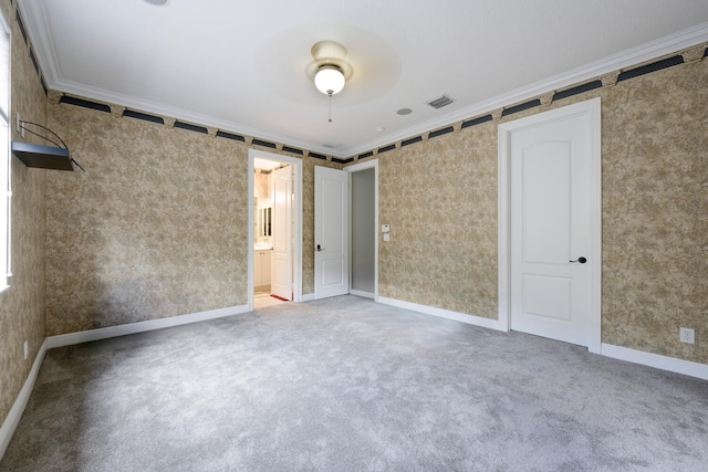 unfurnished bedroom with carpet flooring, ensuite bath, ceiling fan, and crown molding