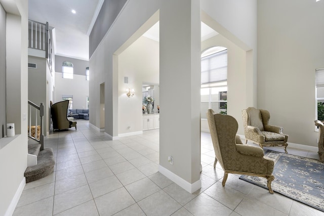 entrance foyer featuring crown molding, light tile patterned floors, and a high ceiling