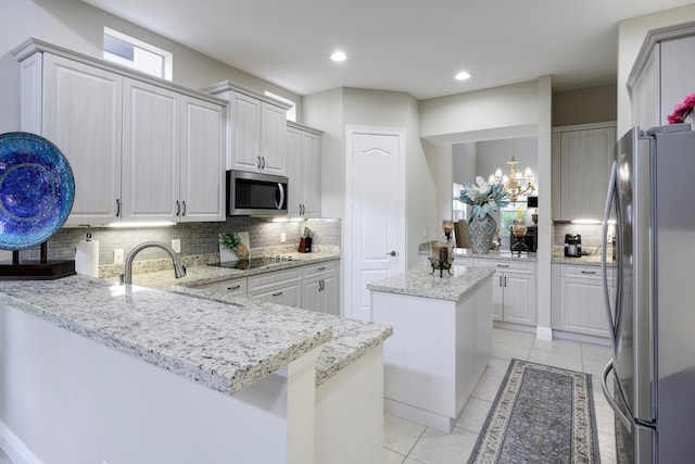 kitchen with a kitchen island, light stone countertops, white cabinets, and stainless steel appliances