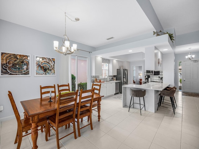 tiled dining area with a chandelier and sink