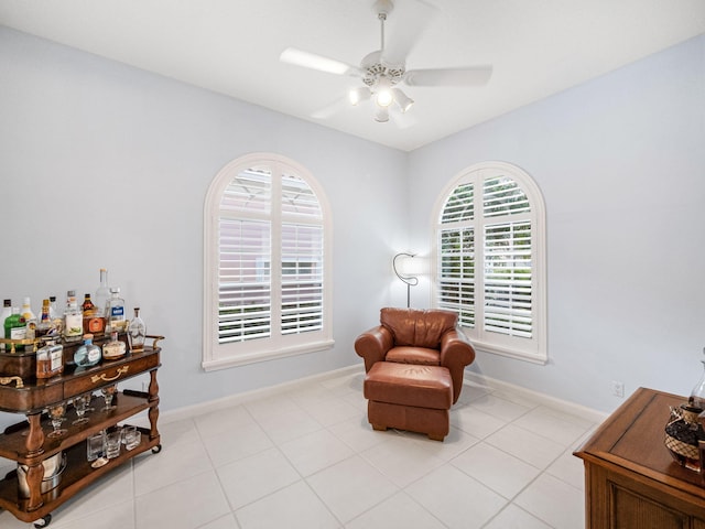 living area featuring ceiling fan, plenty of natural light, light tile patterned floors, and bar