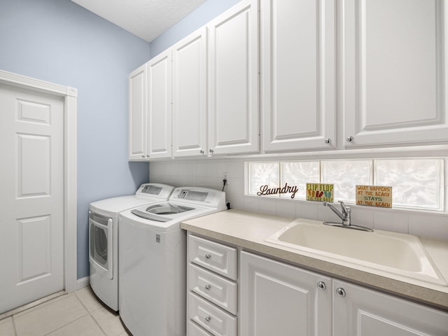 laundry area with cabinets, a textured ceiling, light tile patterned floors, sink, and washer and dryer