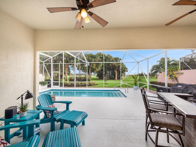 view of pool featuring ceiling fan, a patio, a lawn, a grill, and glass enclosure