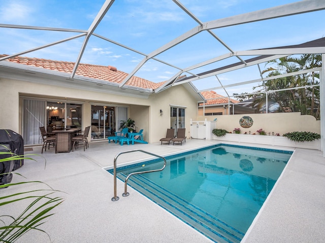 view of pool featuring area for grilling, glass enclosure, and a patio