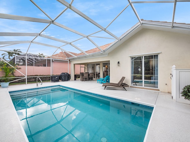 view of pool featuring glass enclosure, outdoor lounge area, and a patio