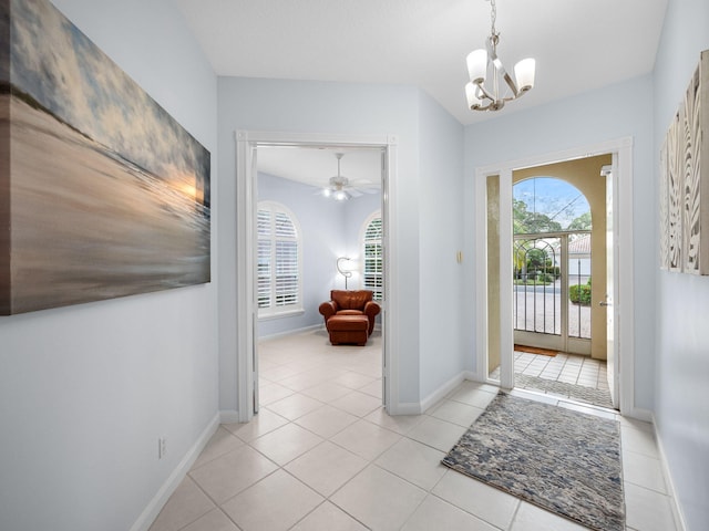 foyer with ceiling fan with notable chandelier and light tile patterned floors