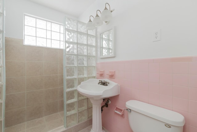 bathroom with a wainscoted wall, tile walls, toilet, and a walk in shower