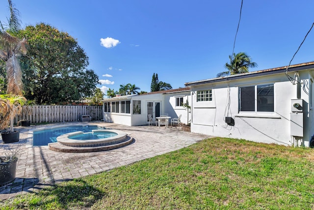 back of house featuring a lawn, a sunroom, fence private yard, a patio area, and stucco siding