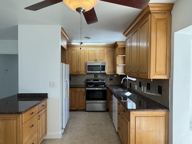 kitchen featuring stainless steel appliances, dark stone counters, backsplash, sink, and ceiling fan