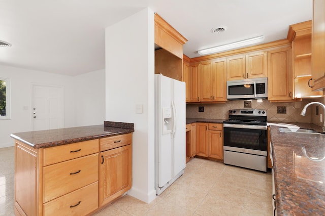 kitchen with visible vents, decorative backsplash, appliances with stainless steel finishes, a peninsula, and a sink