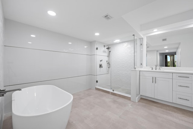 bathroom featuring a shower stall, visible vents, a freestanding bath, and vanity