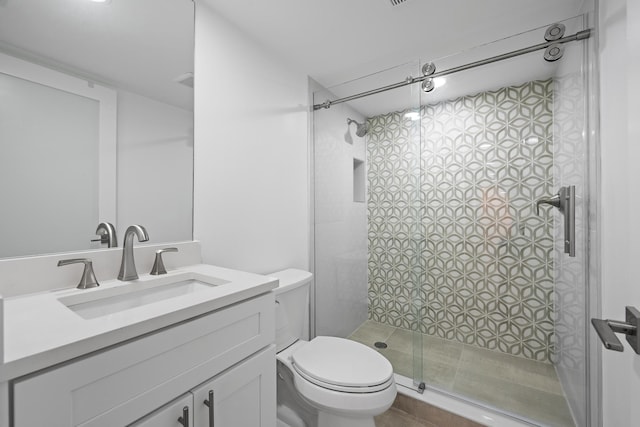 bathroom featuring a shower stall, toilet, and vanity