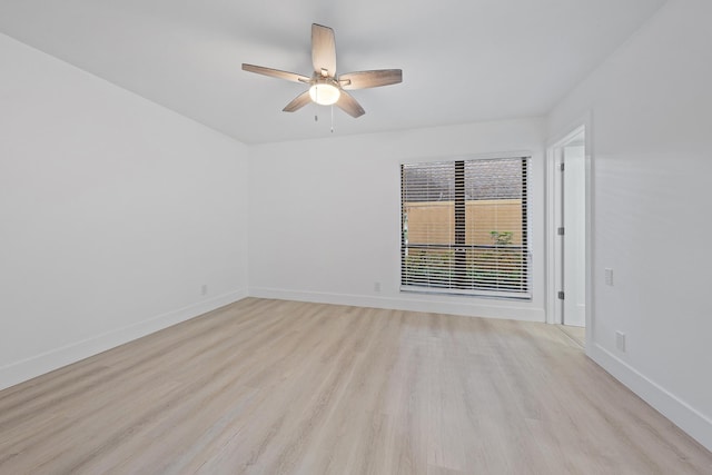 spare room featuring light wood-style floors, baseboards, and a ceiling fan