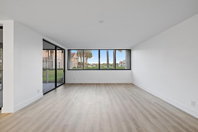 spare room featuring plenty of natural light, baseboards, and wood finished floors