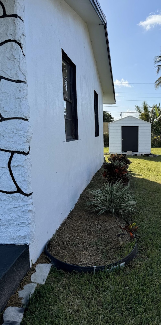 view of side of home with a lawn and a storage unit