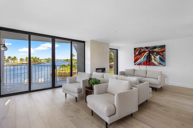 living room featuring a water view, light hardwood / wood-style floors, and a wall of windows