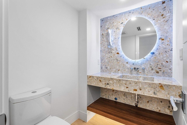 bathroom featuring toilet, wood-type flooring, and sink