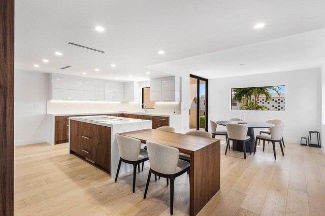 kitchen with double oven, black electric stovetop, a center island, and light hardwood / wood-style flooring