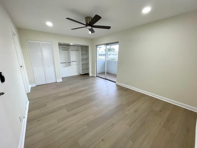 unfurnished bedroom featuring two closets, light hardwood / wood-style flooring, and ceiling fan