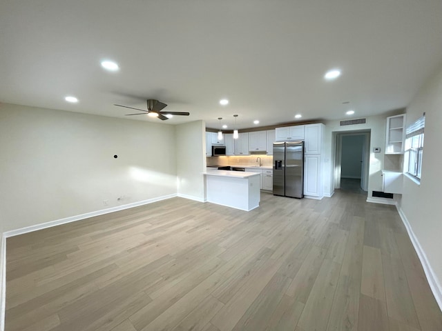 kitchen with white cabinets, stainless steel appliances, decorative light fixtures, and light hardwood / wood-style floors