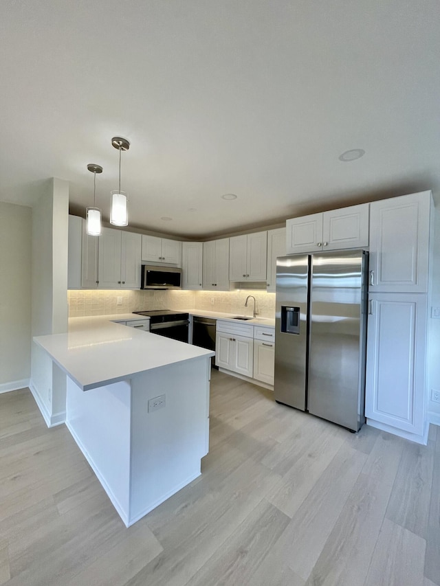 670 Monaco N Unit N, Delray Beach, FL 33446 - kitchen featuring appliances with stainless steel finishes, light wood-style floors, a peninsula, and decorative backsplash
