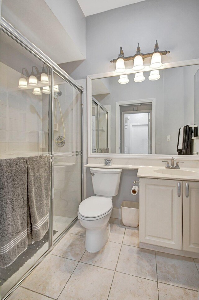 bathroom with tile patterned flooring, vanity, toilet, and a shower with door