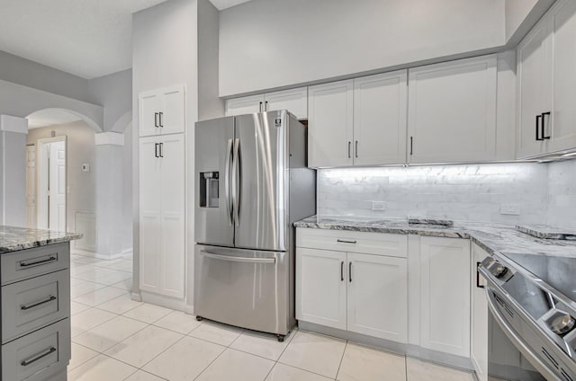 kitchen with decorative backsplash, light stone countertops, stainless steel appliances, and light tile patterned floors