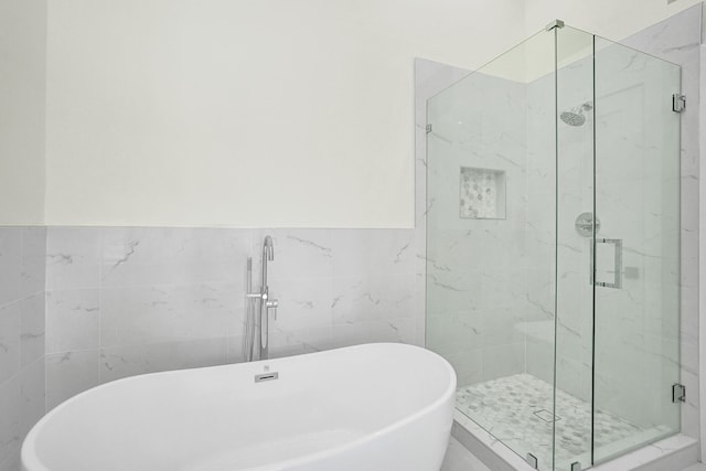 bathroom featuring separate shower and tub and tile walls