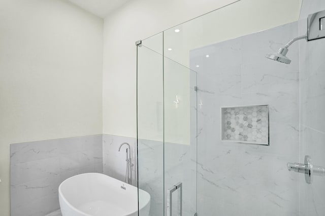 bathroom featuring tile walls and shower with separate bathtub