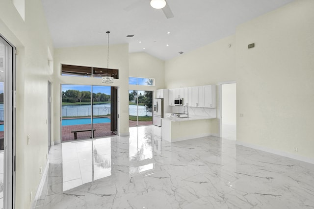 interior space with ceiling fan, a water view, sink, and high vaulted ceiling